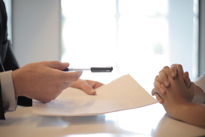 Sales representative handing a pen to a customer to close a deal